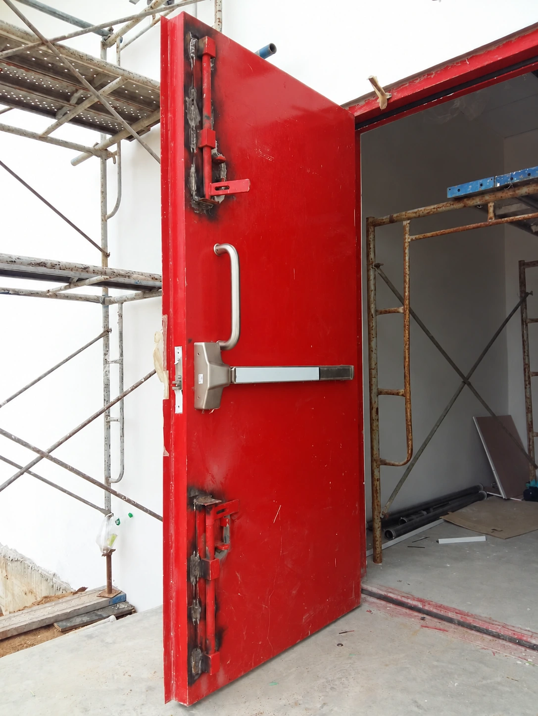 Close-up of a red blast door with hinges and panic bar at Thai Oil